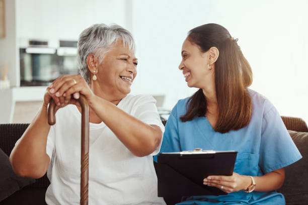 assistenza agli anziani, assicurazione sanitaria e caregiver donna seduta con paziente donna anziana che ride e parla mentre si gode la casa di riposo. hospice della vecchia signora e dell'infermiera femminile con il modulo di controllo sanitario - clinica di allenamento sportivo foto e immagini stock