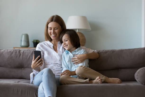 istock Little boy and mom use smartphone sit on sofa indoor 1441252983