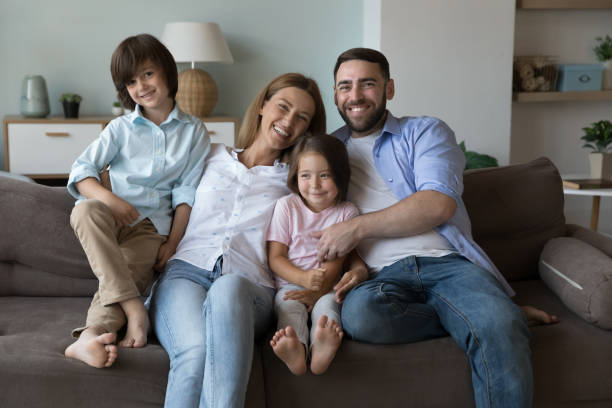 istock Happy couple with children posing for camera seated on couch 1441252984