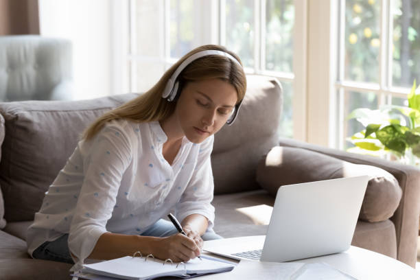 istock Woman writing down notes while listen information through headphones 1441253324