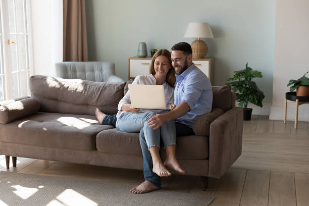 istock Young couple sit on sofa use laptop making online purchases 1441253400