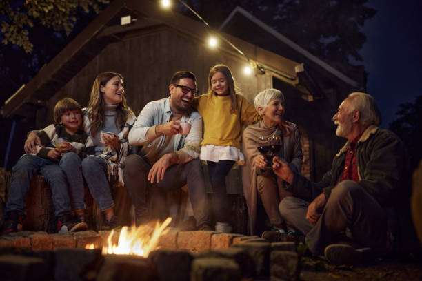família feliz de várias gerações desfrutando da fogueira à noite. - bonfire people campfire men - fotografias e filmes do acervo