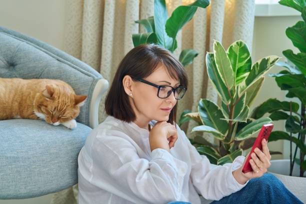 istock Mature woman sitting at home, using smartphone 1441254580