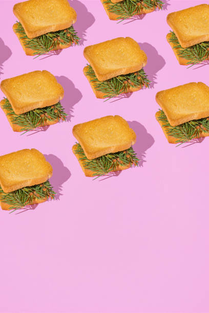 istock Christmas party creative pattern with fir branches between toast bread slices on pastel pink background. 80s, 90s retro aesthetic style romantic concept. Minimal Holiday food idea. 1441259206