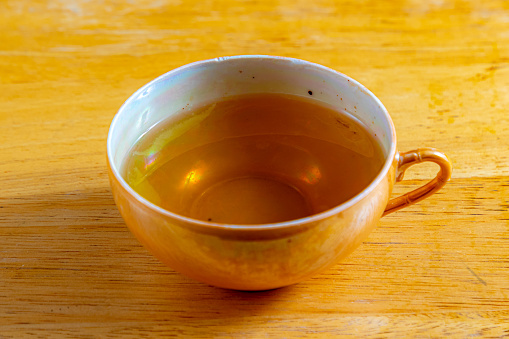 Glass cup of hot ginger tea on the black desk.