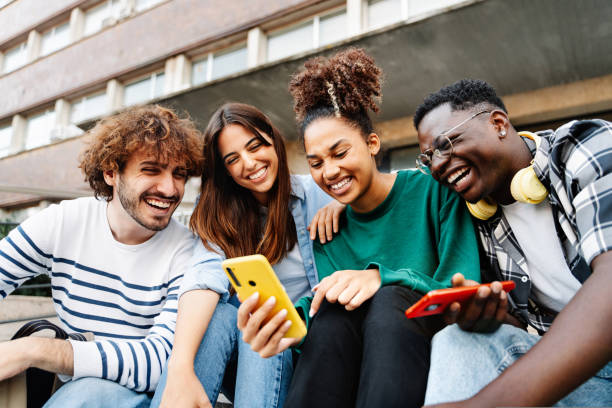 group of university student friends sitting together using mobile phones to share content on social media - generatie z stockfoto's en -beelden