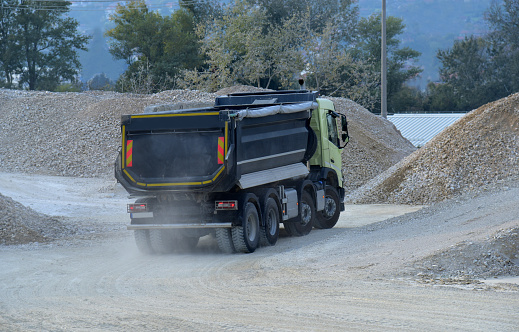 Large dump truck tipper driving in the dust in the quarry