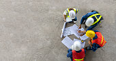 istock Top view of engineer, architect, contractor and foreman meeting at the construction building site with floor plan for real estate development project industry and housing timeline concept 1441270858