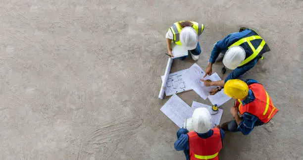 Photo of Top view of engineer, architect, contractor and foreman meeting at the construction building site with floor plan for real estate development project industry and housing timeline concept