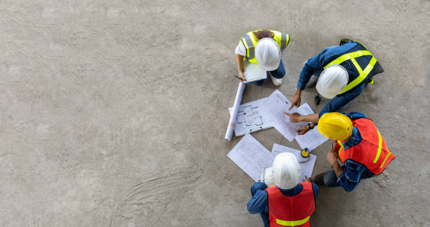 vista superior da reunião de engenheiro, arquiteto, empreiteiro e capataz no canteiro de obras com planta baixa para a indústria de projetos de desenvolvimento imobiliário e conceito de cronograma de habitação - promotor imobiliário - fotografias e filmes do acervo