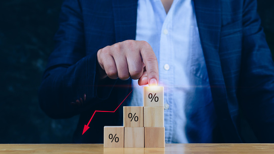 Businessman  hand choose the wooden block with percentage sign and down arrow, monetary growth, interest rate increase, inflation concept,Interest rate financial and mortgage rates concept.