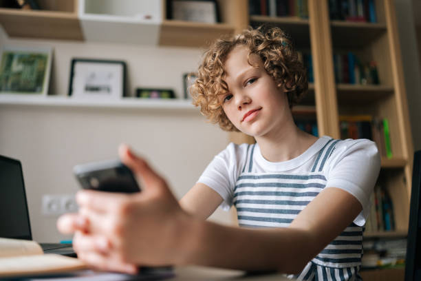 istock Close-up low-angle view of little schoolgirl pupil student e-learning, using smartphone for remote education, checking homework, preparing for test. 1441275817