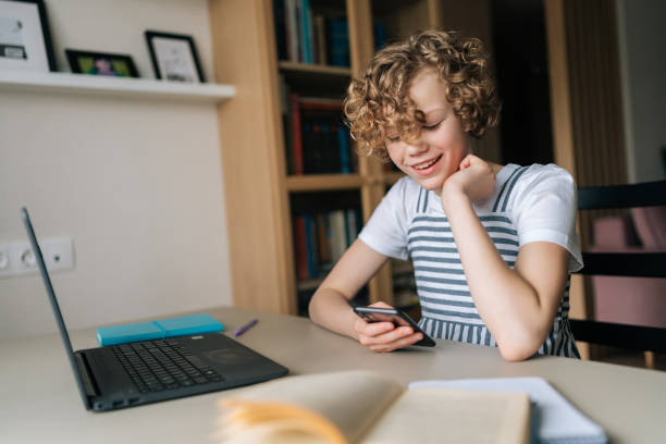 istock Laughing cute little school girl holding and using cellphone, browsing social network apps, surfing internet and scrolling news feed, reading electronic e-book 1441275818