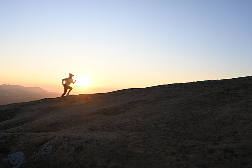 Chinese woman runs uphill in the mountains against the light