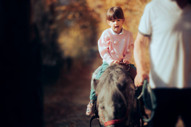 istock Little Girl Riding a Pony Held by an Instructor 1441280720