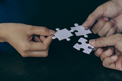 Businessmen join a jigsaw team. Teamwork and cooperation concept handshake puzzle pieces in the office