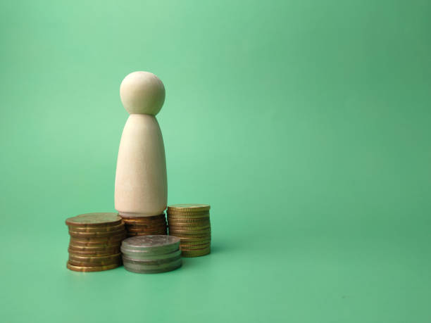 istock Wooden people figures and coins on a green background with copy space. 1441287020