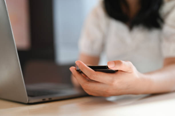 istock Young Asian female using her smartphone while remote working at the coffee shop. cropped image 1441296736