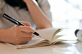 istock Young Asian female writing her diary or taking notes on her notebook. cropped shot 1441297339