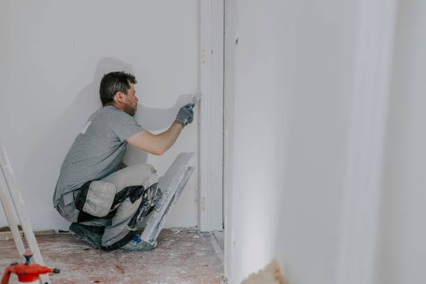 un jeune constructeur plâtre une porte. - plasterer plaster wall dirty photos et images de collection