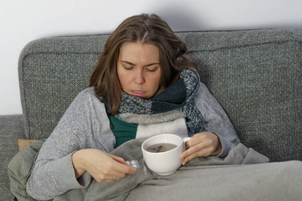 istock young sick girl covered with a blanket taking pills 1441300028