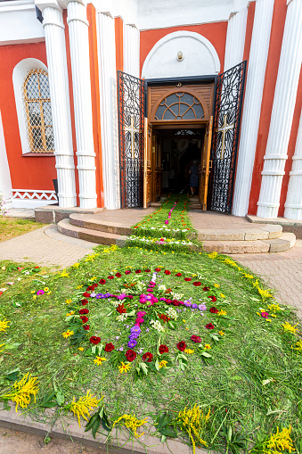 Entrance to an Orthodox church strewn with flowers and grass. Cathedral of the Resurrection of Christ in Staraya Russa, Russia
