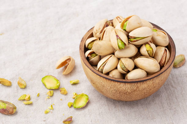 istock Pistachio in wooden bowl on linen table cloth background 1441307855