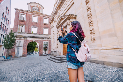 Travel blogger takes photos on the camera of smartphone of the Munster architecture buildings in old town, Germany