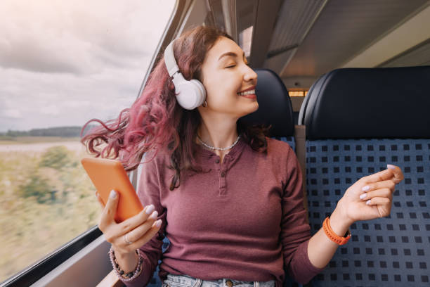 The girl enjoys her favorite music and dances and turns her head during a train ride stock photo