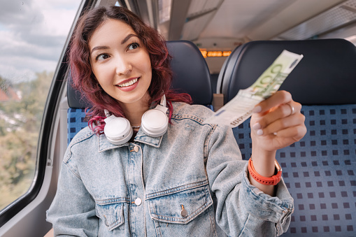 Girl smiles and buys a ticket or other purchases in the train cabin for euro banknotes