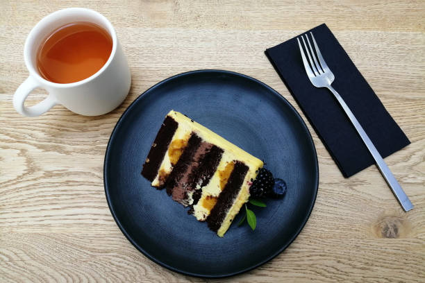 istock creative food design concept, top view, dark blue plate, cup of tea, fork, cake. 1441318016