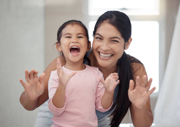 portrait of mother and child, smile with teeth and morning routine. asian woman and toddler girl showing clean teeth after brushing it in the bathroom for fun, learning and child development - offspring child toothy smile beautiful imagens e fotografias de stock