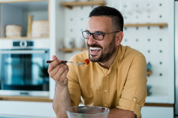Young man eating a salad at home.