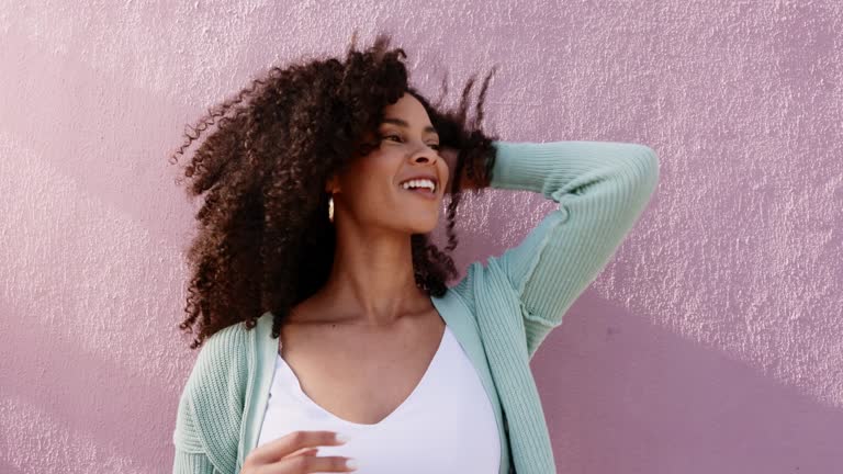 Black woman, happy and retro hair care in sunshine outdoor with freedom, excited and crazy energy on pink background wall. Young Mexico beauty and fashion girl play with hair for natural wellness