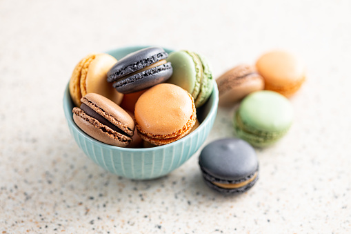 Sweet macaron dessert. Colorful macarons in bowl on the kitchen table.