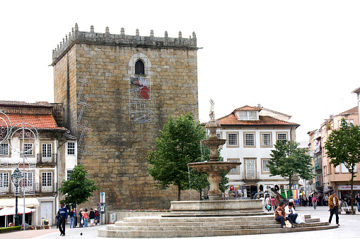 Porta Nova tower, built in XV century, formerly a prison. Ornamental fountain in town square, Barcelos, Portugal..