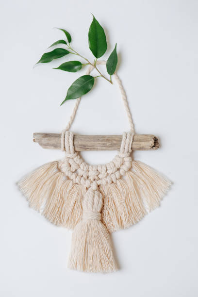 Beautiful macrame hanging on a white wall, decorated with leaves.