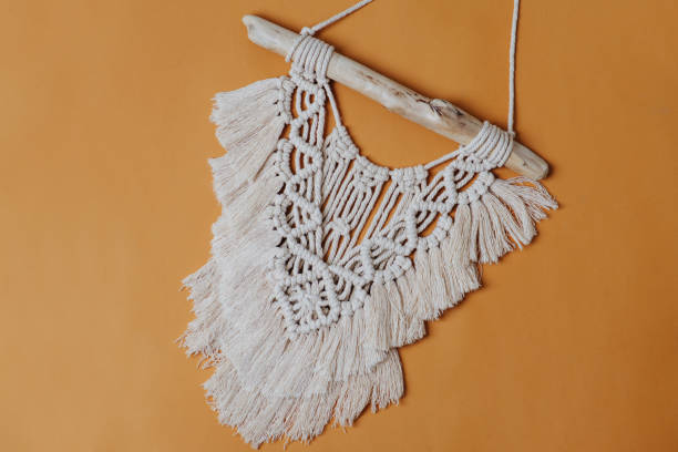 istock Macrame on a stick. Weaved piece af art over orange backround. 1441325879