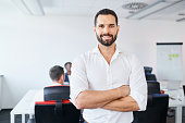 Handsome businessman standing at office. Portrait of smiling man employee in office