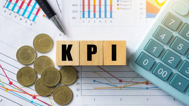 istock KPI, Key Performance Indicator.KPI letter on wooded cube with paperwork calculator and coin on a board room table. business goals, performance results and indicators. 1441329686