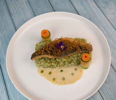 Recipe for fried fillet of sea bass with herb risotto, white wine sauce, fresch creme, roll of carrot and courgette strips, candied and fried lemon peel, High quality photo