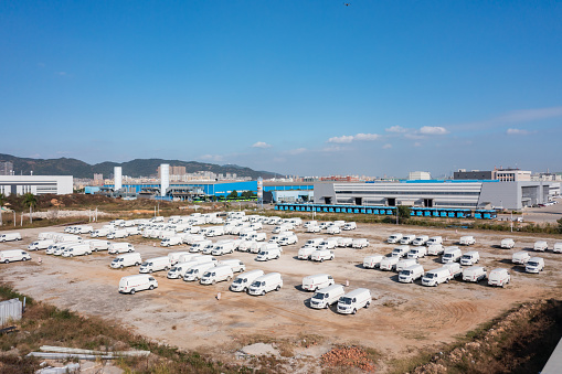 Outdoor parking lot under blue sky full of small white cars