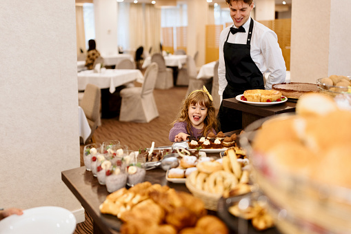 Little girl looking at cakes on a buffet table