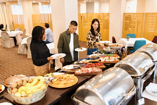 Food Buffet Catering Dining Eating Party Sharing Concept. Multi ethnic people group catering buffet food breakfast indoor in luxury hotel restaurant with meat colourful fruits and vegetables