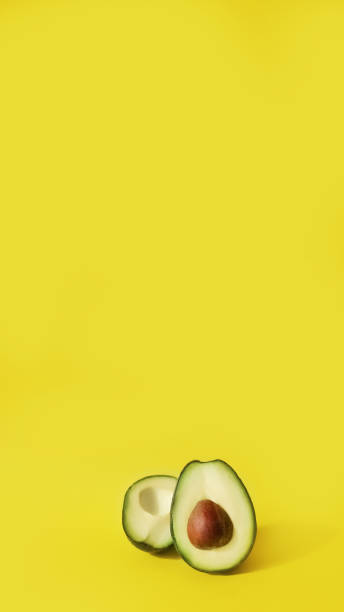 istock two halves of cut avocado fruit on yellow background, vertical, 16:9 1441334467