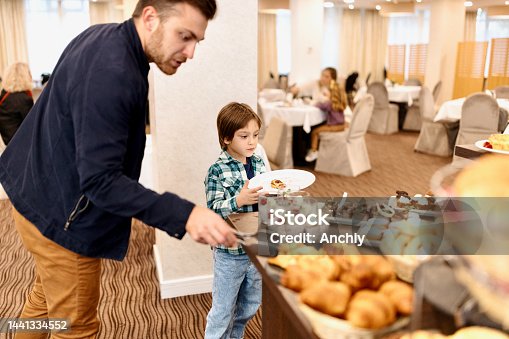 istock Father and son take the food from buffet breakfast table at the hotel 1441334552