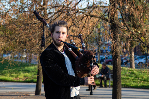 Wroclaw, Poland - November 12, 2022: Young man playing bagpipes for donations on the Xawerego Dunikowskiego boulevard