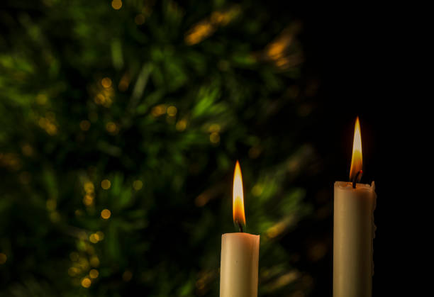 Light of white candles with Christmas tree against black background