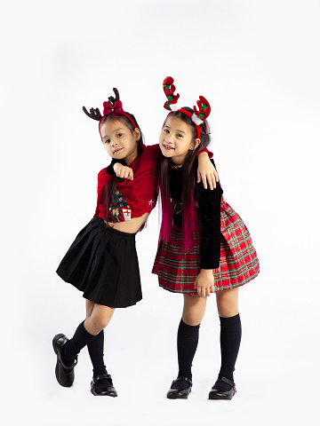 Cute asian kids in christmas theme costume wearing reindeer horns headband standing posing full length white background. Merry Christmas.