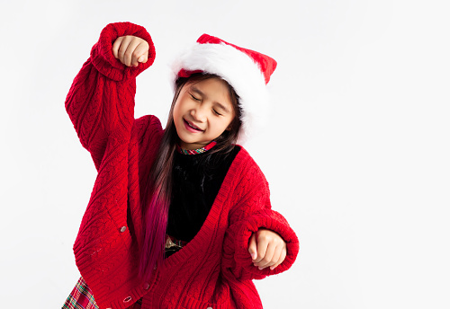 Asian kid in red sweater wear santa hat posing on white background.